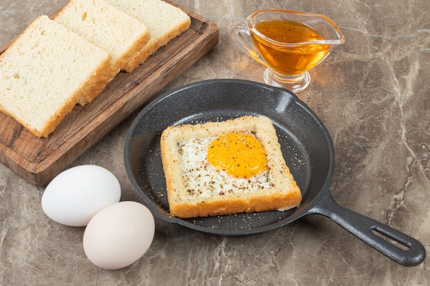 Un plato de una rebanada de pan integral con huevo frito y especias.