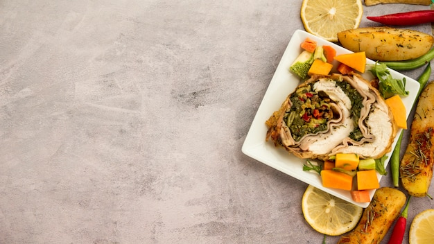 Plato con rollo de pollo y verduras en mesa de concreto