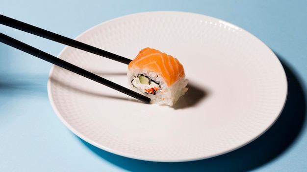 Plato con rollo de sushi y palillos