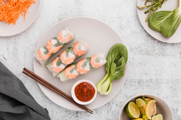 Foto gratuita plato de rollos de camarones con palillos y lima