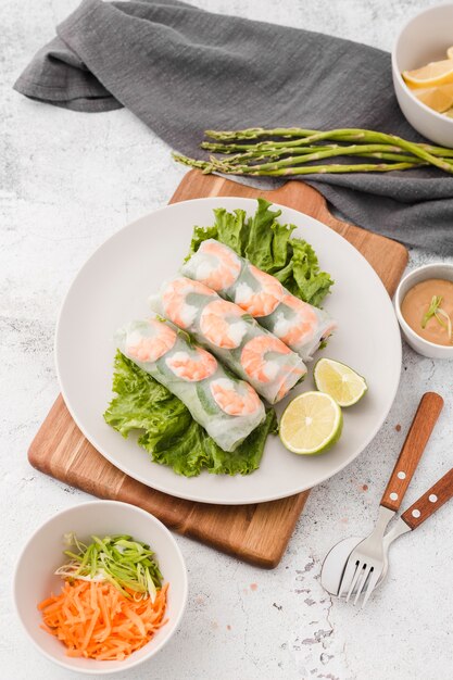 Plato de rollos de camarones sobre tabla de cortar con espárragos