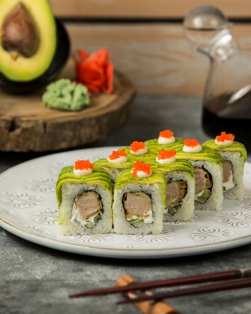 Foto gratuita plato de rollos de sushi cubierto con aguacate, crema y tobiko rojo