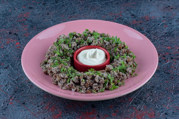 Un plato rosa de carne picada con guisantes y hierbas.