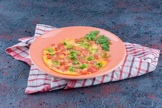 Un plato rosa de tortilla con verduras.