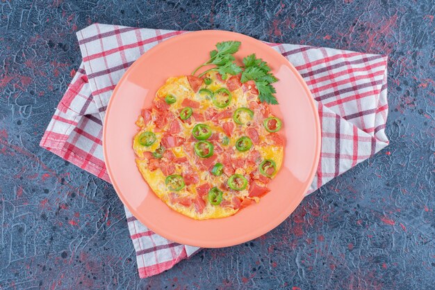 Un plato rosa de tortilla con verduras.