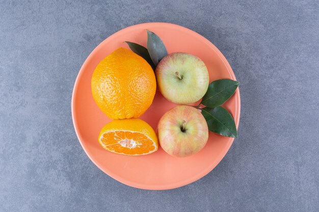 Un plato de sabrosa manzana y naranjas en la superficie oscura