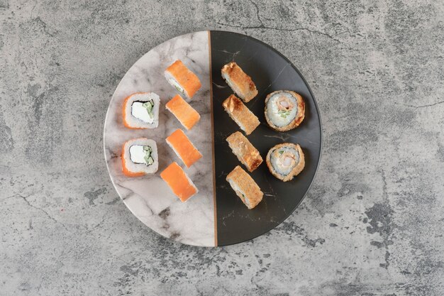 Plato de salmón y rollos de sushi calientes colocados sobre una mesa de mármol