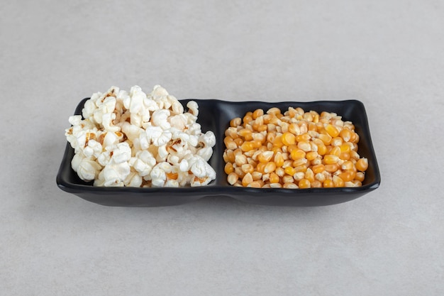 Plato de servicio de dos caras con granos de maíz y palomitas de maíz en la mesa de mármol.