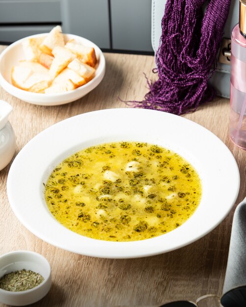 Un plato de sopa de albóndigas dushbara azerbaiyana adornado con hojas de menta seca