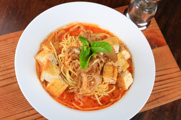 Plato de sopa con espaguetis, trozos de pan y decorado con verduras