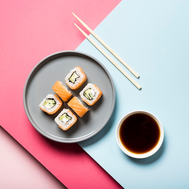 Plato de sushi plano con palillos y salsa de soja
