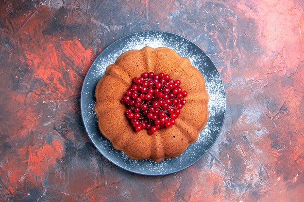 Plato de tarta de un apetitoso pastel con grosellas rojas sobre la mesa rojo-azul