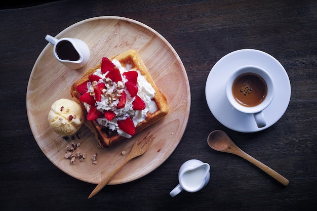 Plato con una tostada con nata y fresas y un café