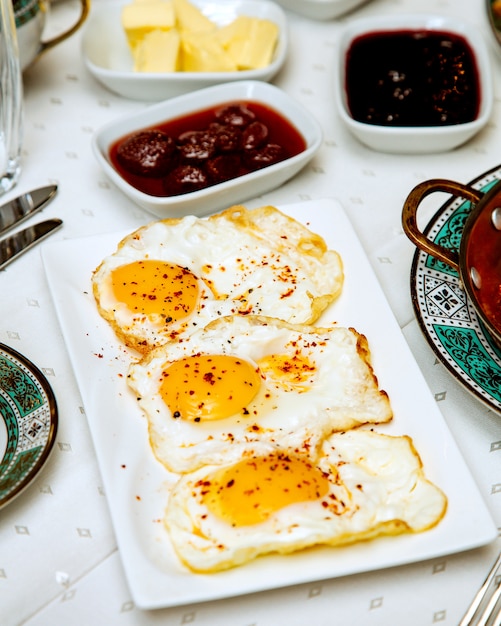 Foto gratuita un plato de tres huevos con pimiento rojo.