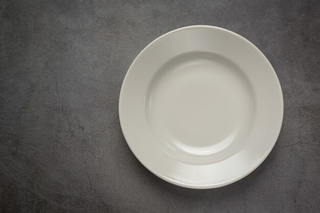 Un plato vacío redondo blanco sobre una superficie oscura.