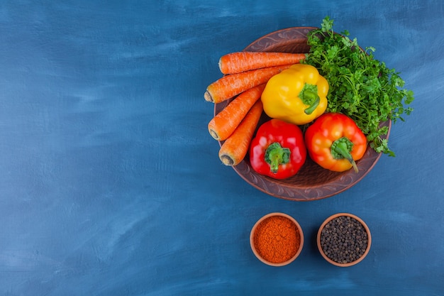 Plato de varias verduras frescas maduras en el cuadro azul.