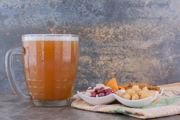 Plato de variedad de bocadillos y cerveza en la mesa de mármol. Foto de alta calidad