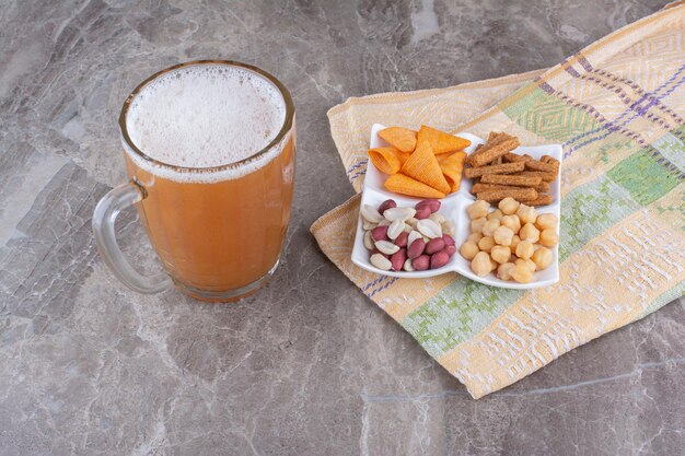 Plato de variedad de bocadillos y cerveza en la superficie de mármol