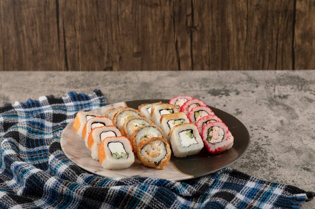 Plato de varios deliciosos rollos de sushi sobre mesa de mármol