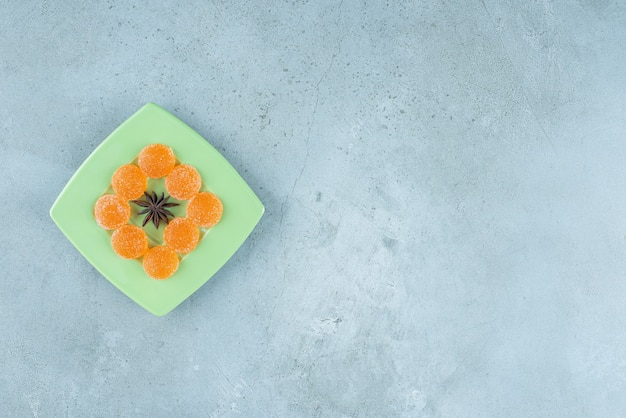 Un plato verde de anís estrellado y mermeladas de naranja.