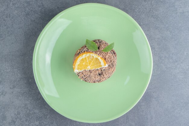 Un plato verde con cupcake y rodaja de limón.