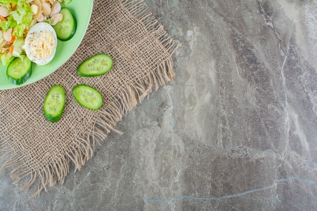 Plato verde de deliciosa ensalada fresca sobre superficie de mármol.