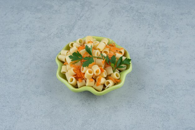Un plato verde de macarrones y brócoli sobre fondo blanco. Foto de alta calidad