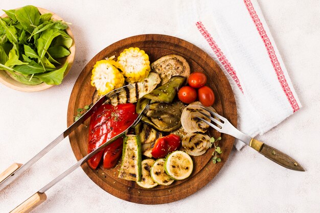 Plato con verduras asadas y cubiertos en mesa