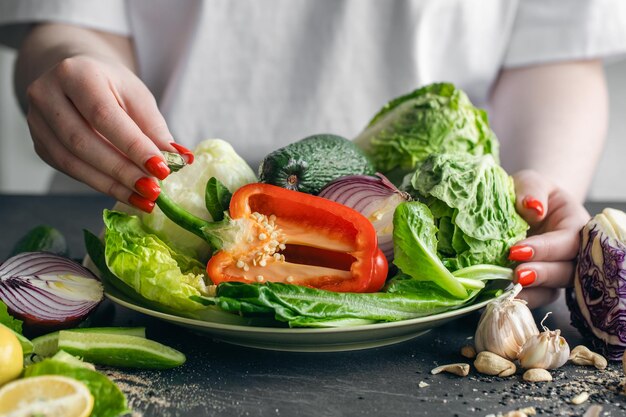 Un plato con verduras frescas en manos femeninas en el primer plano de la cocina