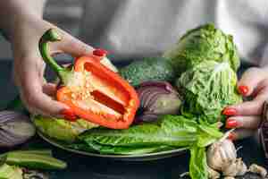 Foto gratuita un plato con verduras frescas en manos femeninas en el primer plano de la cocina