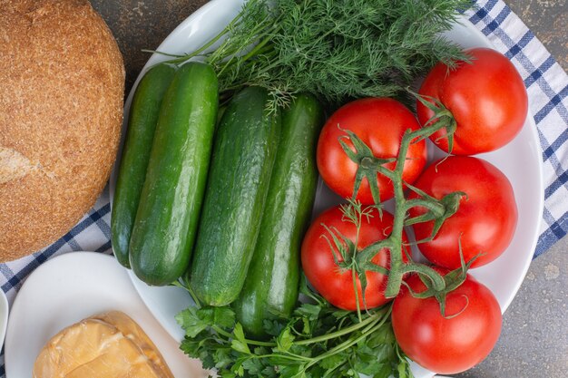 Plato de verduras y pan sobre mármol.