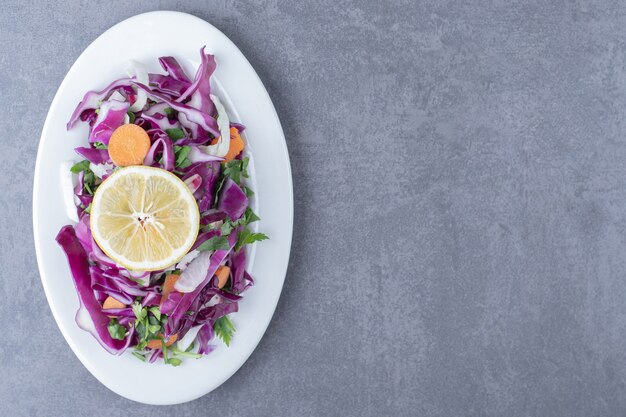 Un plato de verduras ralladas con limón, sobre la superficie de mármol.