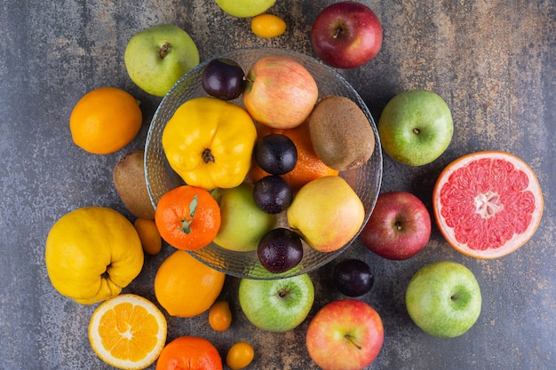 Plato de vidrio de frutas frescas encima de muchas frutas.