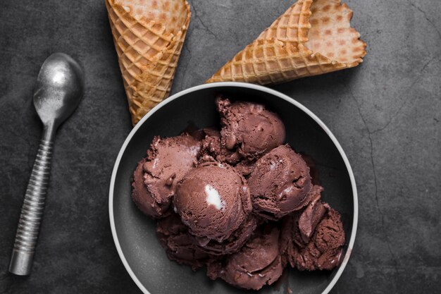 Plato de vista superior con bolas de helado de chocolate y conos al lado