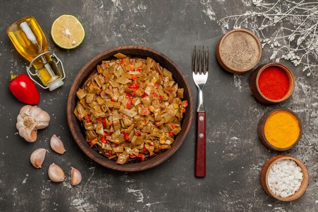 Plato de vista superior y especias plato de horquilla de judías verdes tomates al ajillo pimientos cuatro tazones de especias y una botella de aceite