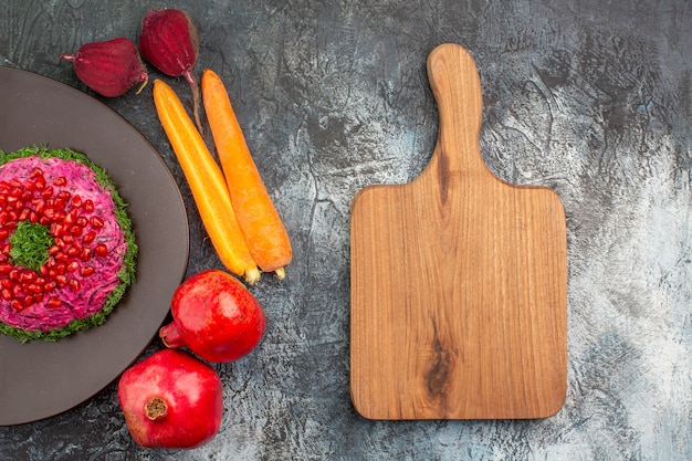 Plato de vista superior de primer plano un plato apetitoso granadas verduras la tabla de cortar