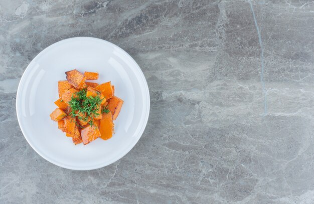 Un plato de zanahorias en rodajas, sobre la mesa de mármol.