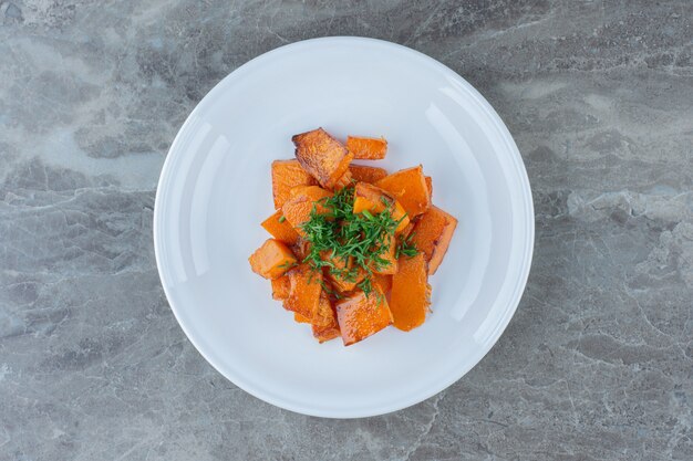 Un plato de zanahorias en rodajas, sobre la mesa de mármol.