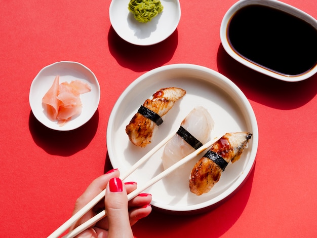 Platos blancos con sushi y wasabi sobre un fondo rojo.