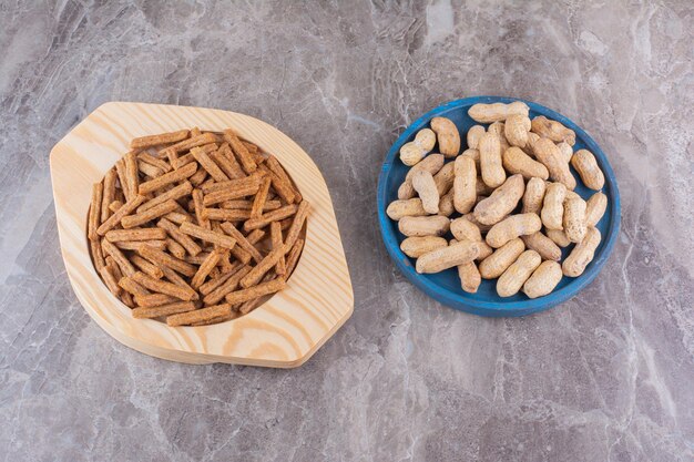 Platos de cacahuetes y galletas en superficie de mármol. Foto de alta calidad