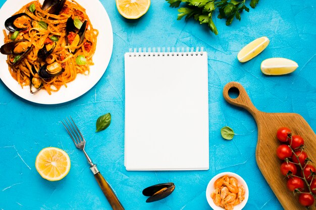 Platos de mariscos planos con la libreta.