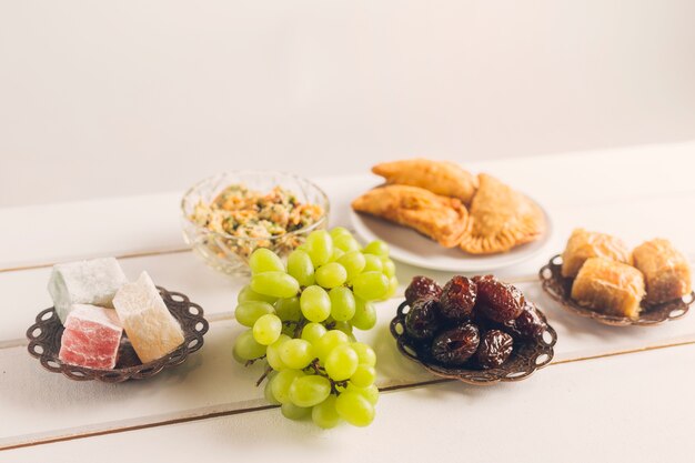 Platos orientales y uvas sobre mesa.