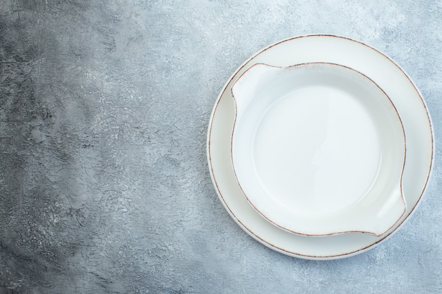 Platos de sopa blancos vacíos en el lado izquierdo en la mitad de la superficie de color gris claro oscuro con superficie angustiada con espacio libre