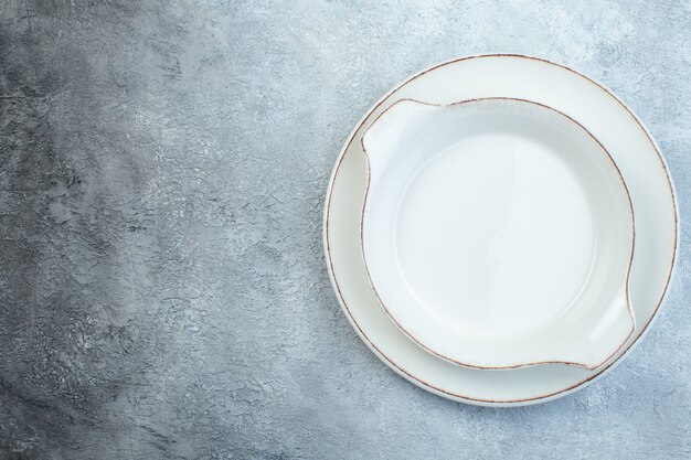 Platos de sopa blancos vacíos en el lado izquierdo en la mitad de la superficie de color gris claro oscuro con superficie angustiada con espacio libre