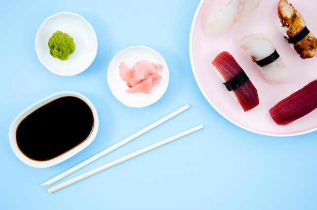 Platos con sushi y salsa de soja sobre un fondo azul.