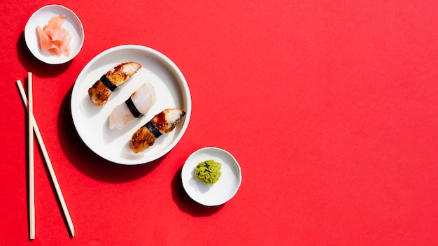 Platos con sushi y wasabi sobre un fondo rojo.