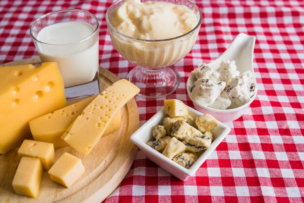 Platos y tabla de cortar con queso fresco cerca de vaso de bebida