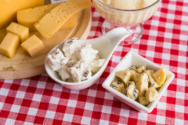 Platos y tabla de cortar con queso fresco en mesa.