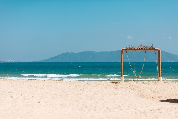 Playa de arena con arco de madera decorativo cerca del mar