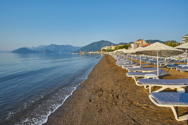 Playa de arena sin gente y con tumbonas sombrillas palmeras Marmaris